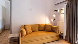 A room with a sofa, a lamp, a radiator, and a door. - Drakatos X Apartment (Lefkada)