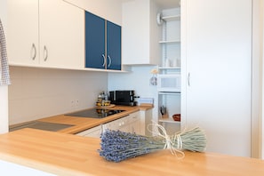 A kitchen with white cabinets, a microwave, and a wooden countertop. - Beautiful Apartment Near Monaco (Beausoleil)