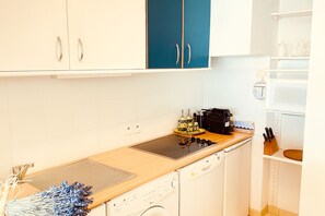 A kitchen with white cabinets, a dishwasher, a stove, and a coffee maker. - Beautiful Apartment Near Monaco (Beausoleil)