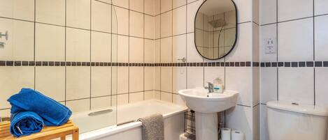 A bathroom with a bathtub, sink, toilet, and a mirror.