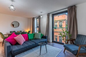 A modern living room with a sofa, a chair, a dining table, and a large window with a view of a brick building. - Top Floor Vibes Lgbtq Hotspot City Nights (Liverpool)