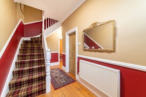 A staircase with red and beige walls, a patterned carpet, and a white radiator. - By Sefton Lark Lane W M Games Parking (Liverpool)