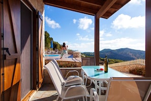 An outdoor patio with a table and chairs, a pool, and a view of mountains.