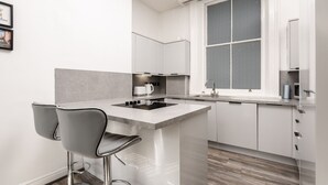 Una cocina moderna con una isla central, taburetes de bar y un ventanal con un diseño texturizado.