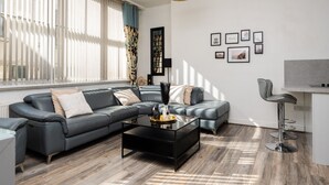Una sala moderna con un sofá modular, una mesa de centro de vidrio y una zona de bar.