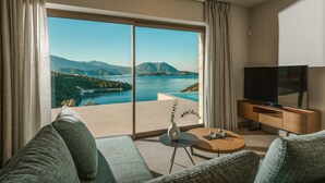 Een moderne woonkamer met een groot raam, een flatscreen-televisie, een bank en een kleine tafel met een vaas.