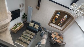 A modern living room with a sofa, a small table, a potted plant, and a stained glass window. - Rare Historic Church Stained Glass Parking (Liverpool)