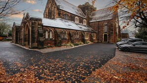 A church with a brick exterior, arched windows, and a paved driveway. - Rare Historic Church Stained Glass Parking (Liverpool)