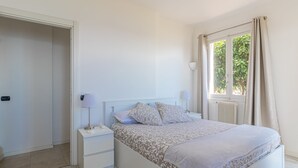 A bedroom with a bed, bedside tables, a window with curtains, and a radiator. - Family Villa-sea View Pool and Garden Near Monaco (Roquebrune-Cap-Martin)