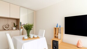A modern dining area with a white table, chairs, and a wooden sideboard with a speaker and decorative items. - High-end Residence With Pool and Panoramic Views (Beausoleil)