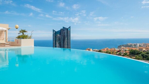 A hotel with a pool overlooking the ocean, a modern building, and a clear sky. - High-end Residence With Pool and Panoramic Views (Beausoleil)