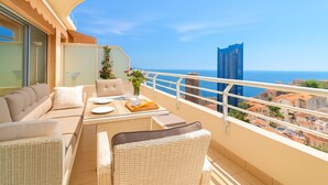 A balcony with a sofa, dining table, and chairs, overlooking a cityscape and the sea. - High-end Residence With Pool and Panoramic Views (Beausoleil)