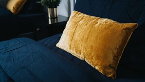 A bed with a blue comforter and a single gold-colored pillow. - Next to LFC W M Desk Space City Links (Liverpool)