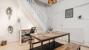 A modern interior with a staircase, a dining table with placemats, a bench, and a radiator. - Next to LFC W M Desk Space City Links (Liverpool)