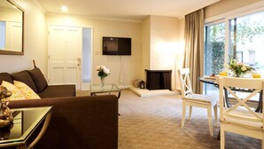 A living room with a sofa, a glass coffee table, a fireplace, a TV, and a dining area with a table and chairs. - Napa Escape Luxe King Bed Near Wineries Spa (Napa)