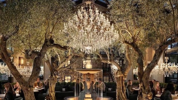 An outdoor dining area with trees, a fountain, and chandeliers. - Luxe Napa Escape King Bed Near Top Wineries (Napa)