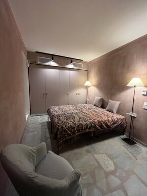 A bedroom with a bed, two bedside lamps, a chair, and a wardrobe. - Pasparo Estate in Samos (Samos)