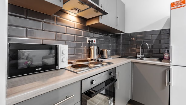 A modern kitchen with a built-in microwave, stove, oven, and a stainless steel sink. - Great for Longer Stays W M Smart TV Parking (Liverpool)