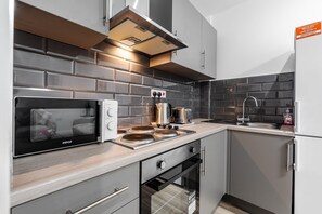 Eine moderne Küche mit integriertem Mikrowellenherd, Herd, Backofen und einer Spüle aus Edelstahl.
