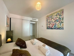 A hotel room with a bed, pillows, a painting, a lamp, and a wardrobe. - One Bedroom Flat Near Monaco (Beausoleil)