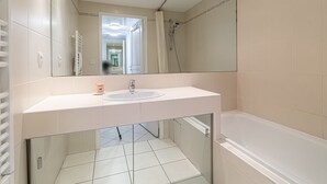 Een moderne badkamer met een wit wastafelmeubel, spiegel en bad.
