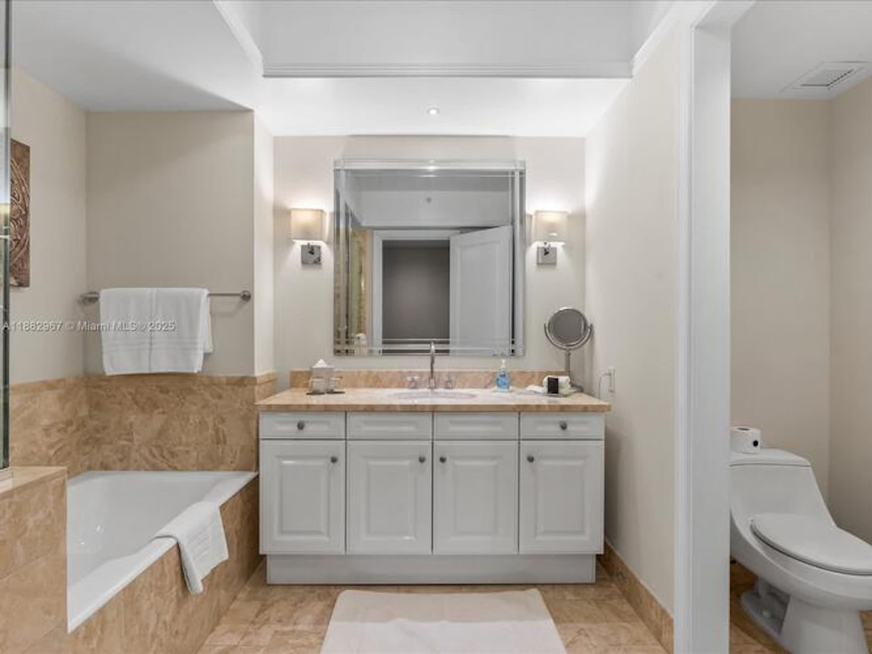 A modern bathroom with a bathtub, a sink with a mirror, and a toilet.