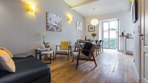 Ein modernes Wohnzimmer mit einer Couch, Sesseln, einem Esstisch und Kunstwerken an den Wänden.