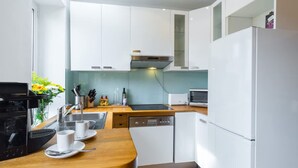 Eine moderne Küche mit weißen Schränken, einem Geschirrspüler, einer Mikrowelle und einer Kaffeemaschine.