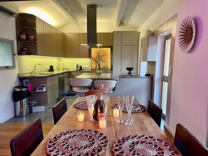 A modern kitchen with a dining area, featuring a central island, built-in appliances, and a view of the dining room. - Renovated House in the Center of Beausoleil (Beausoleil)
