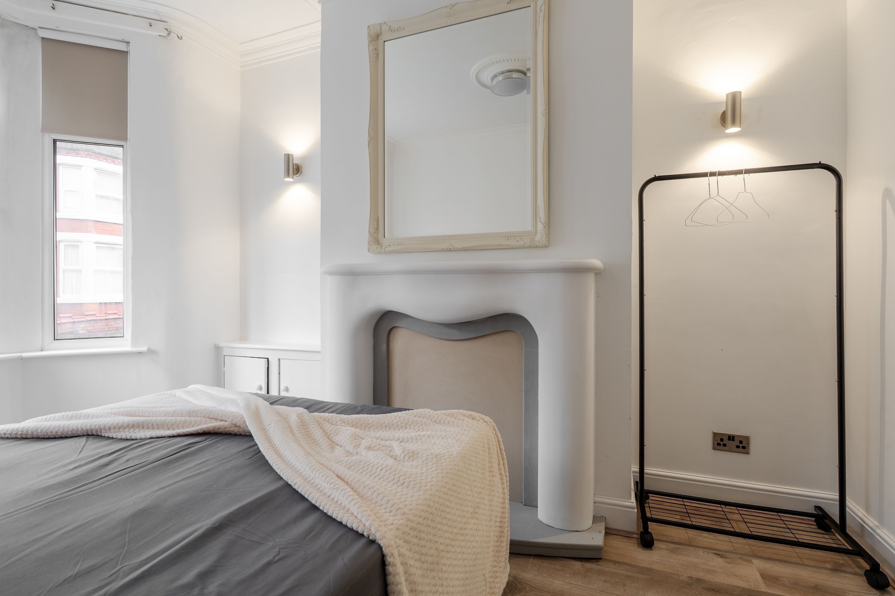 Una camera da letto con un letto, uno specchio, un termosifone e un armadio.