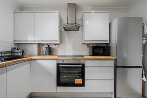 A modern kitchen with white cabinets, a stainless steel range hood, a built-in oven, a microwave, and a refrigerator. - Homey Stay Prime Anfield Spot Fast Wifi (Liverpool)