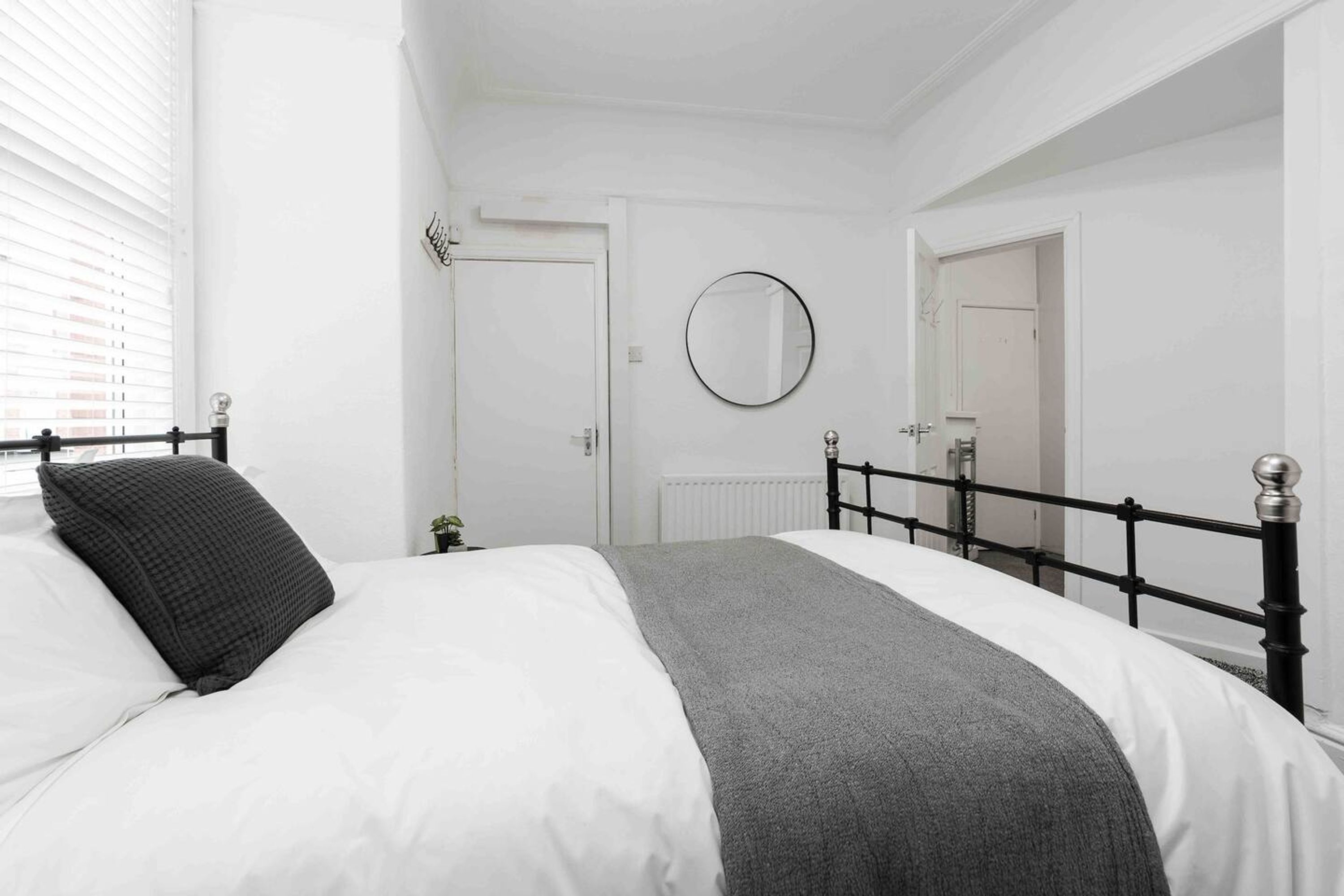 A bedroom with a bed, a round mirror, and a door.