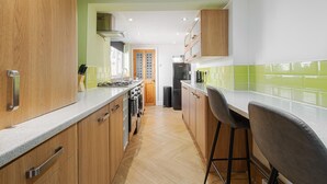 A kitchen with wooden cabinets, a countertop, a stove, and a refrigerator. - 10 Mins to Crosby Beach Ensuite WC Parking (Liverpool)
