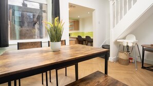 A dining area with a wooden table, chairs, a potted plant, and a view of a kitchen and staircase. - 10 Mins to Crosby Beach Ensuite WC Parking (Liverpool)