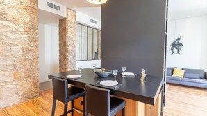 A modern dining area with a stone accent wall, a dark dining table, and black chairs. - Elegant Bel Epoque Apartment in Center of Menton (Menton)