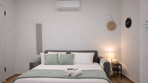 A neatly made bed with pillows, a bedside lamp, and a wall-mounted air conditioner. - Cozy Studio in the Heart of Menton Walk Everywhe (Menton)