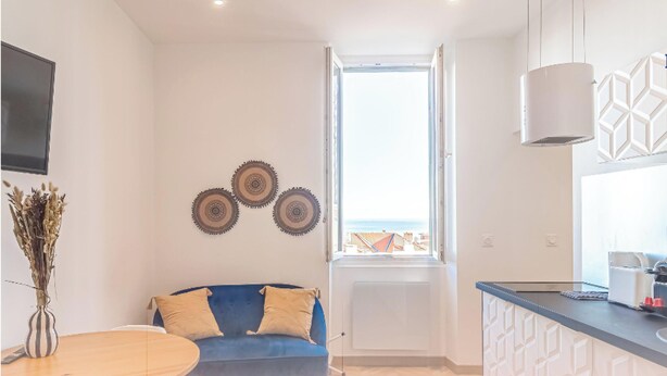 Una cocina moderna con un sofá azul, placas decorativas en la pared y vistas a través de una ventana.