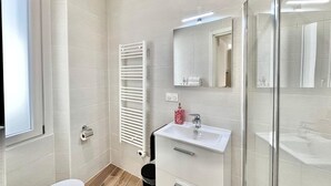 A modern bathroom with a white sink, mirror, and towel rack. - Studio in the old Town of Menton (Menton)
