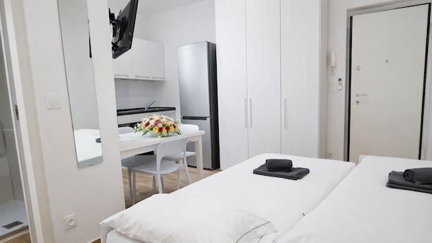 A hotel room with a bed, a desk with a chair, a refrigerator, and a bathroom. - Studio in the old Town of Menton (Menton)