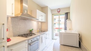A modern kitchen with a gas stove, oven, and a built-in microwave. - Menton Garavan 2BR by the sea Parking (Menton)