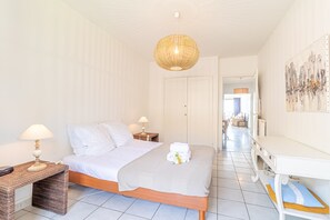 A bedroom with a bed, bedside tables, a lamp, a hanging light fixture, a painting, and a hallway leading to a living area. - Menton Garavan 2BR by the sea Parking (Menton)