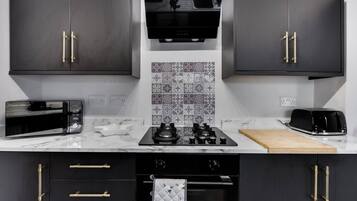 A modern kitchen with dark cabinets, a microwave, a toaster, and a stove.