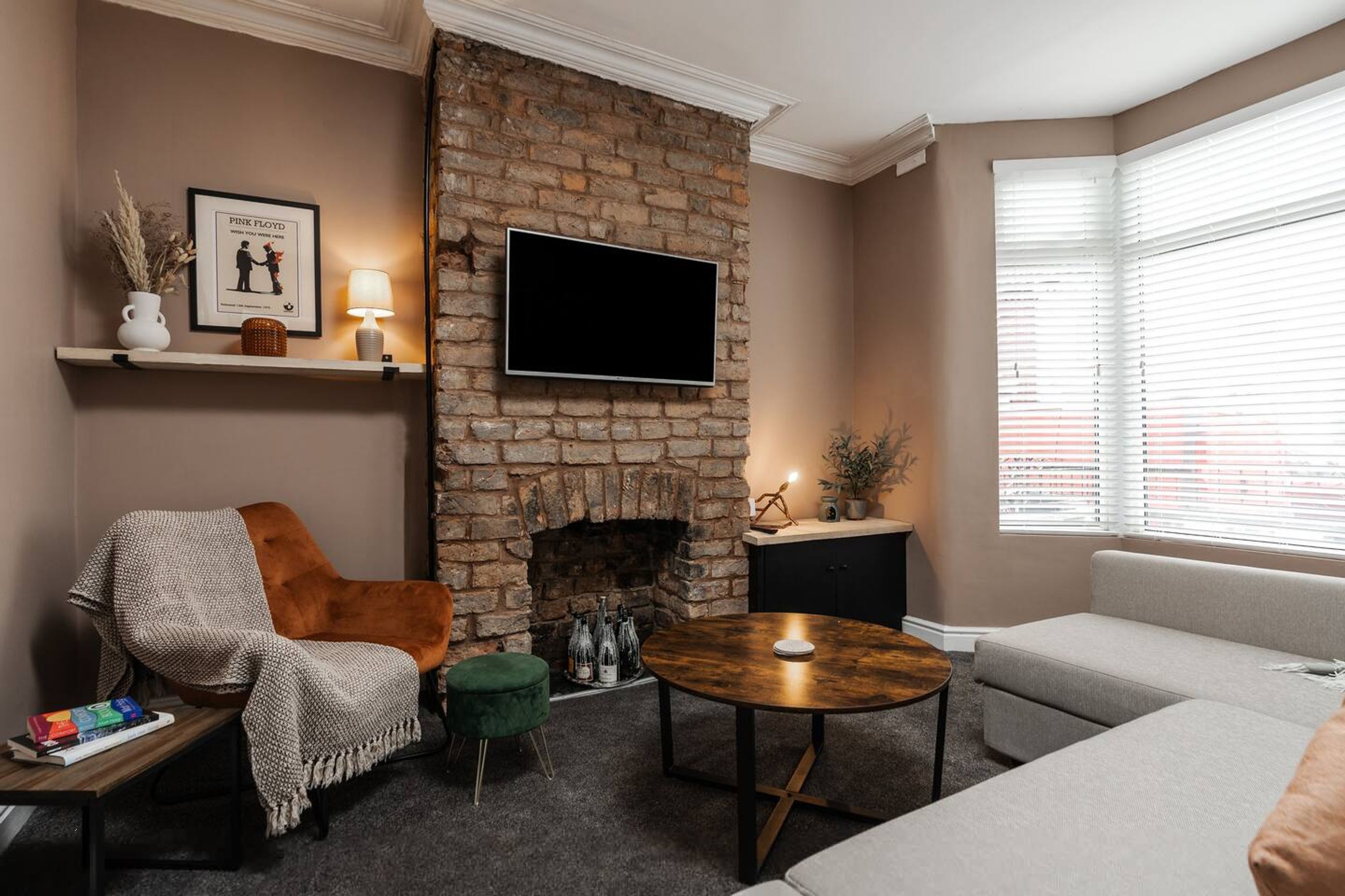 Una sala de estar con chimenea de ladrillo, un televisor de pantalla plana, un sofá, una mesa de centro y una silla.