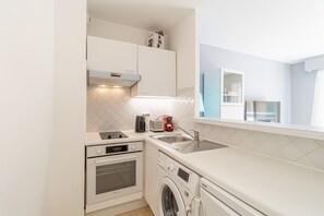 Eine kompakte Küche mit Backofen, Waschmaschine und Spüle.
