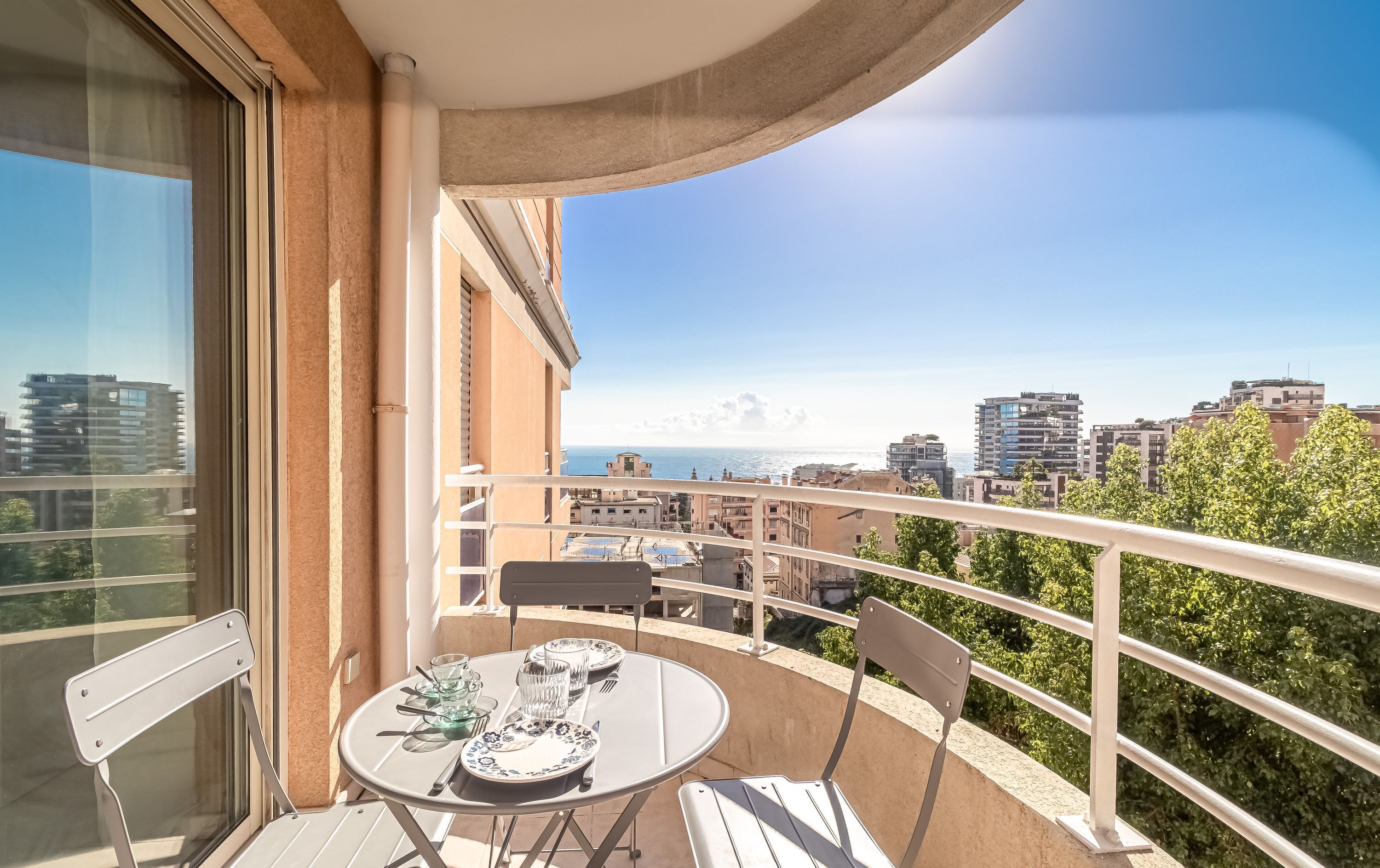 Un balcón con una mesa lista para dos personas, con vista a la ciudad y al mar.