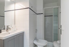 Ein modernes Badezimmer mit Waschbecken, Spiegel, Toilette und Dusche.