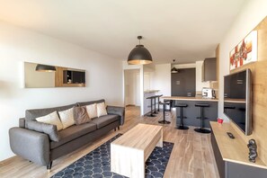 Ein modernes Wohnzimmer mit einer Couch, einem Couchtisch und einer Küchenzeile mit Barhocker.