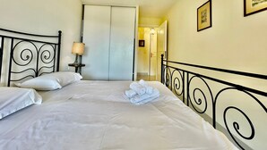 Habitación de hotel con cama, mesita de noche, lámpara, armario y un cuadro en la pared.