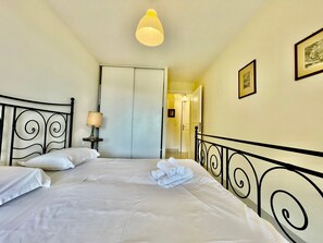 Ein Hotelzimmer mit Bett, Nachttisch, Lampe, Kleiderschrank und einem gerahmten Bild an der Wand.