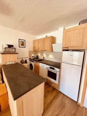 Eine kompakte Küche mit Waschmaschine, Geschirrspüler, Backofen und Kühlschrank.
